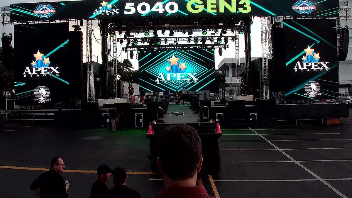 APEX 5040 GEN3 stage at dusk with teal LED wall graphics and full line array