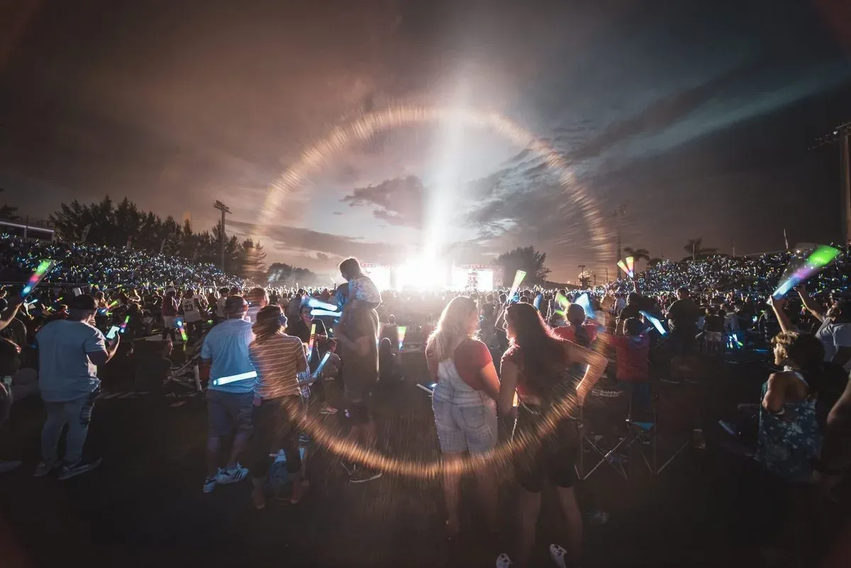 Concert crowd under a ring of light at a Reflections production